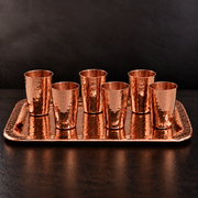 Set of six hammered pure copper shot cups on a matching rectangular serving tray for an elegant spirits flight.