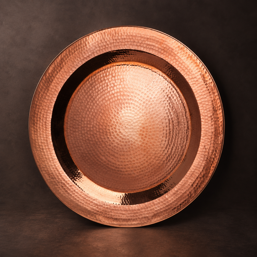 14-inch hand-hammered round copper platter with a dazzling, reflective finish for elegant table service and decor.