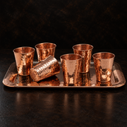 Six hammered copper shot cups arranged on a matching rectangular serving tray for an elegant spirit flight display.