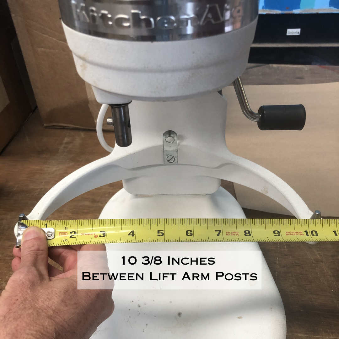 Measuring tape showing 10 3/8 inches between the lift arm posts of a white KitchenAid professional stand mixer.