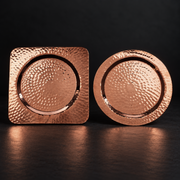 Hand-hammered pure copper coasters in round and square shapes, 5.625 inches, for elegant bottle and table protection.