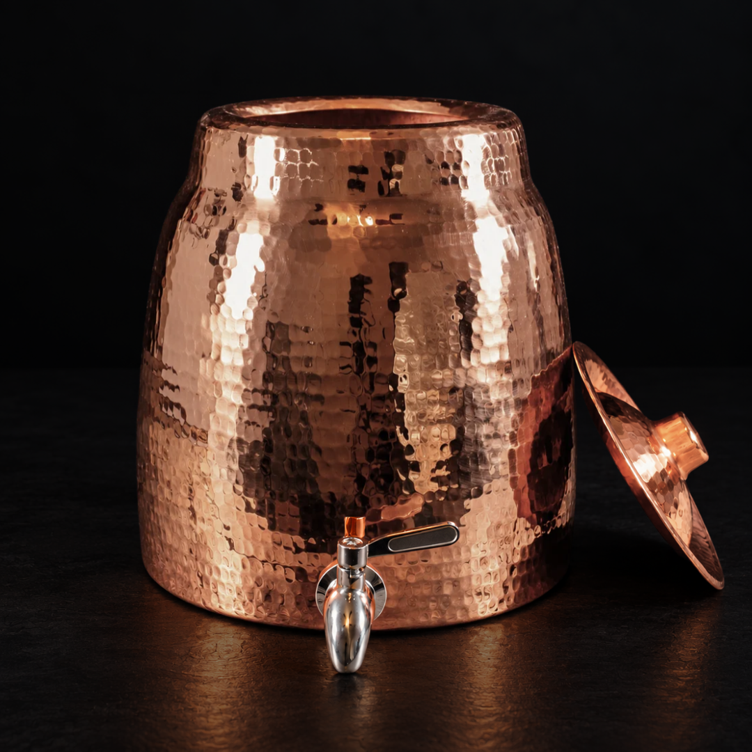 Handmade 2-gallon hammered copper water dispenser with a sleek metal spigot and matching lid on a black background.