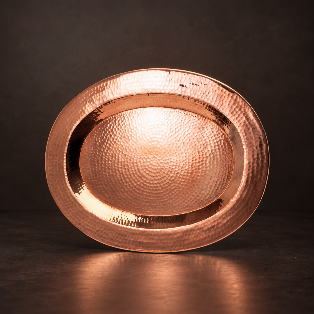 Hand-hammered oval copper platter with a brilliant reflective finish, perfect for elegant serving or wall decor.