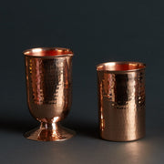 Two hammered copper cocktail glasses: one with a pedestal base, one flat-bottomed.