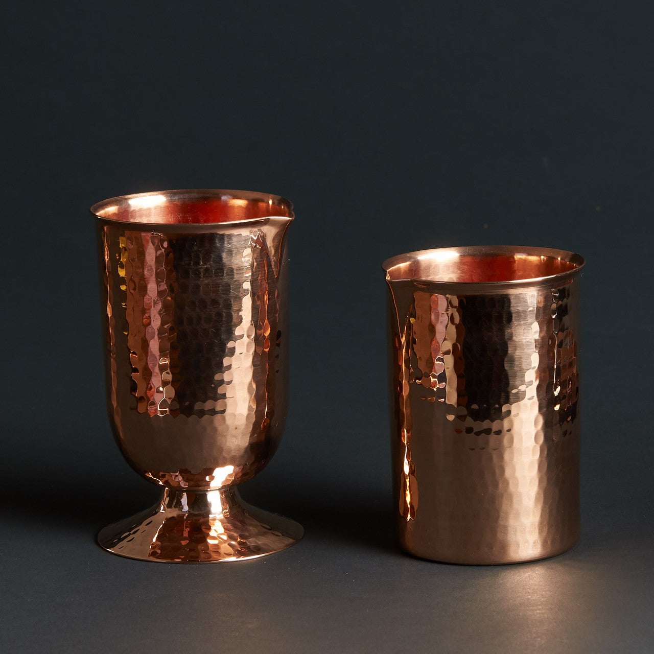 Two hammered copper cocktail glasses: one with a pedestal base, one flat-bottomed.