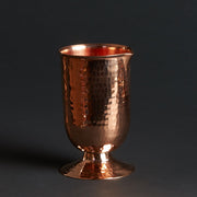 Hammered copper cocktail glass with a rounded pedestal base, 20-ounce capacity.