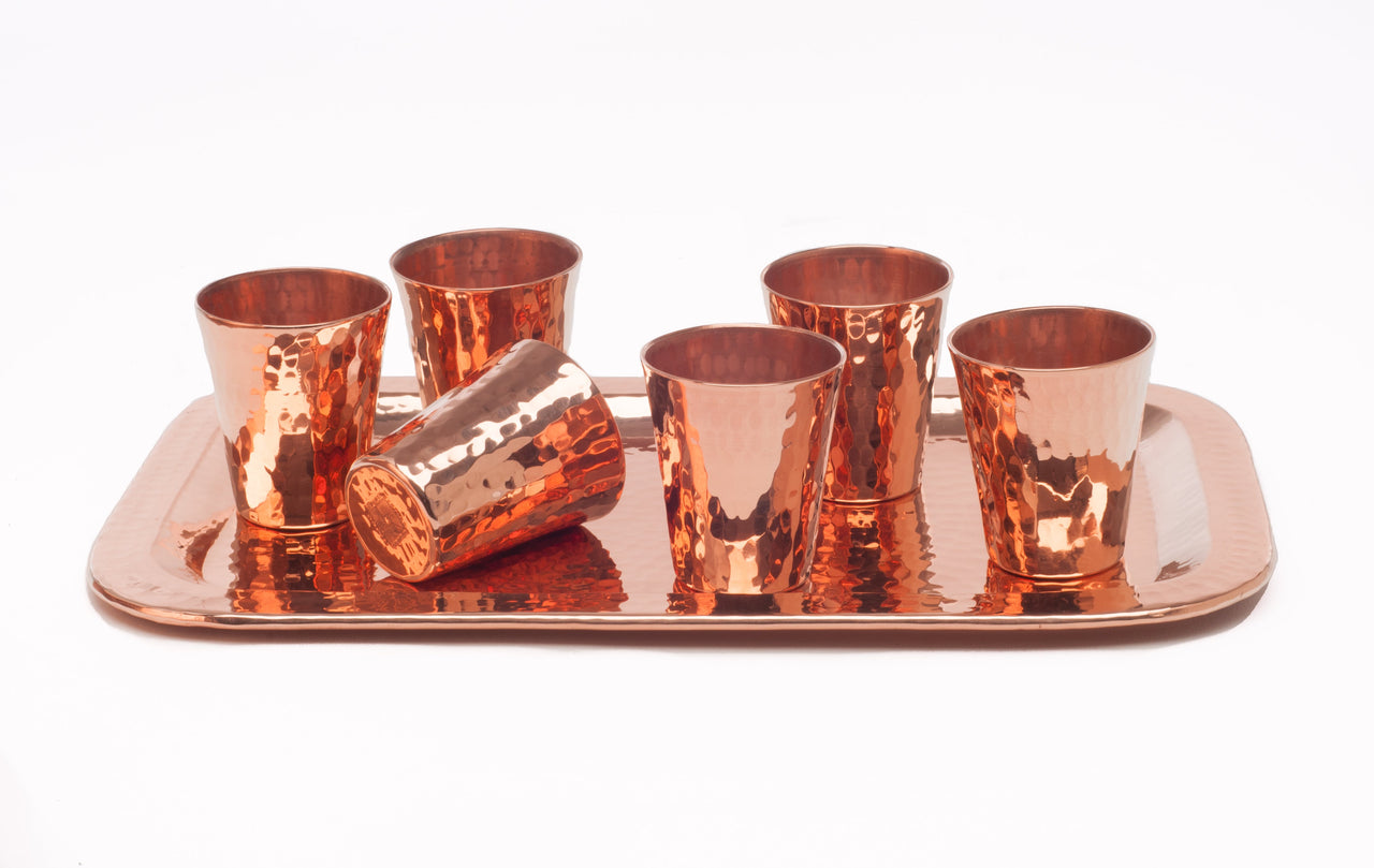 Six hammered copper shot cups on a rectangular copper serving tray.
