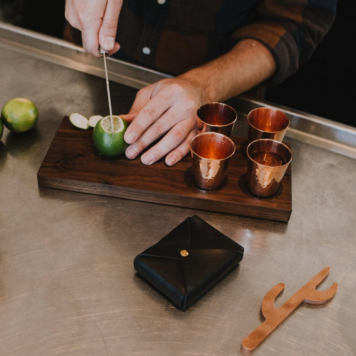 Hand-carved walnut serving board with four hand-forged copper shot glasses for luxury mezcal service.