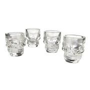 Set of 4 clear glass 1.5 oz skull-shaped shot glasses with detailed facial features.