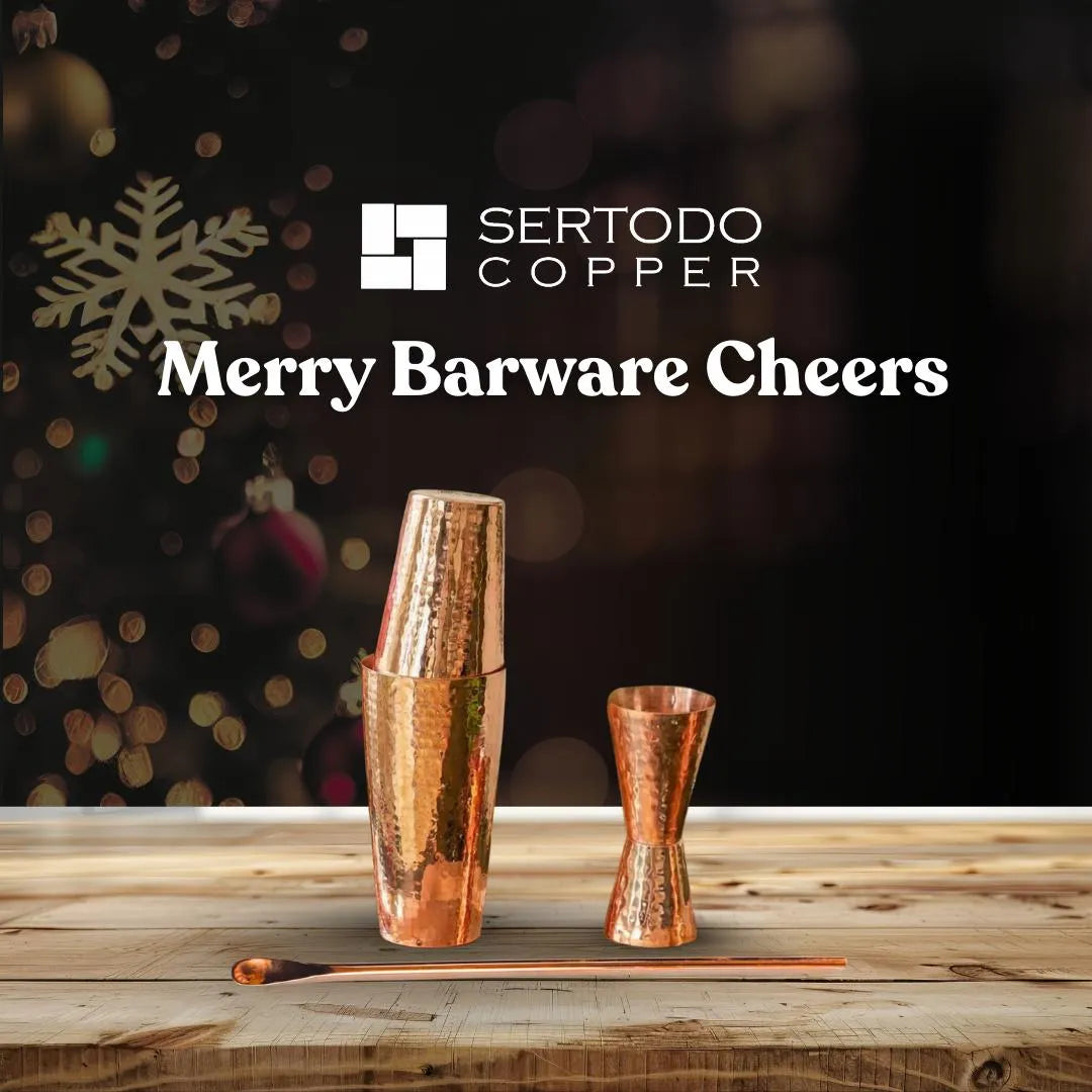 Handcrafted copper cocktail shaker, double jigger, and bar spoon on a wooden surface, festive background.
