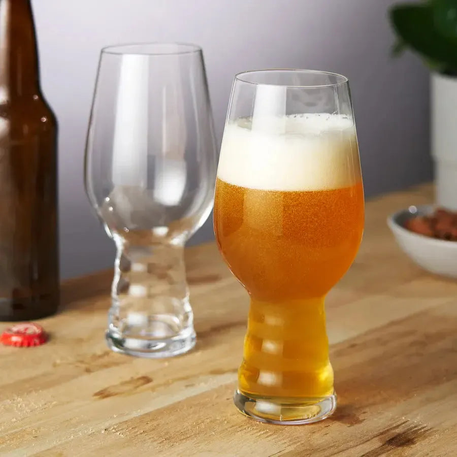 Two clear crystal Spiegelau Craft IPA beer glasses, one filled with golden beer and foam.