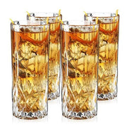Set of 4 clear lead-free crystal highball glasses with cut-crystal details, filled with amber cocktails and lemon peels.