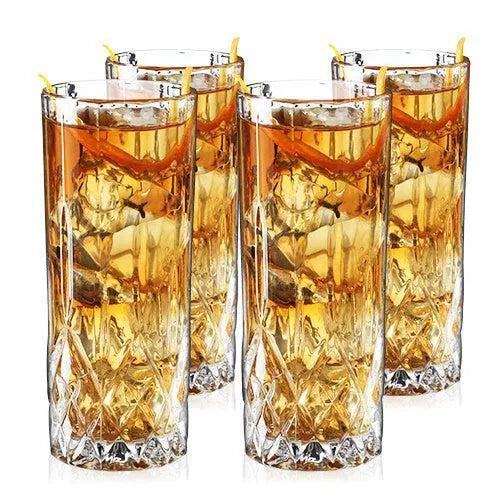 Set of 4 clear lead-free crystal highball glasses with cut-crystal details, filled with amber cocktails and lemon peels.