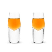 Two clear lead-free crystal shot glasses with heavy bases, filled with amber liquid.