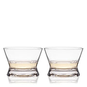 Two clear, lead-free crystal tequila tasting glasses with flared lips and wide bowls, each holding amber liquid.